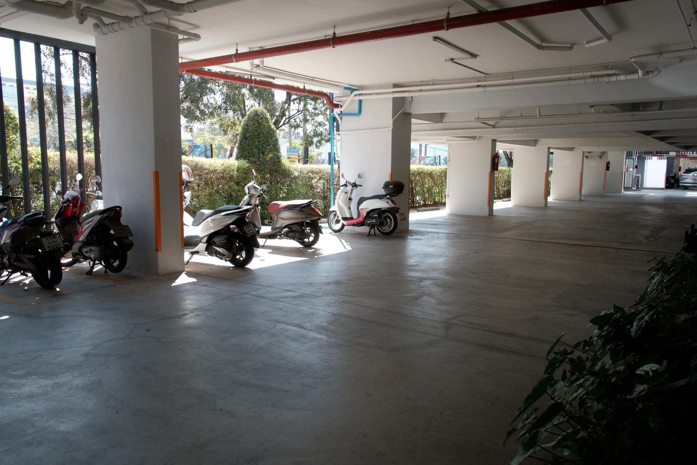 Covered parking area with scooters and motorbikes in a well-lit residential building