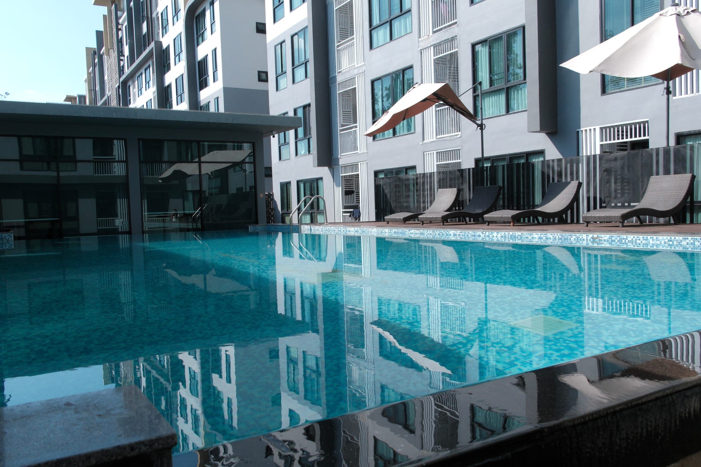 Outdoor swimming pool with turquoise water, lounge chairs, and residential tower in the background